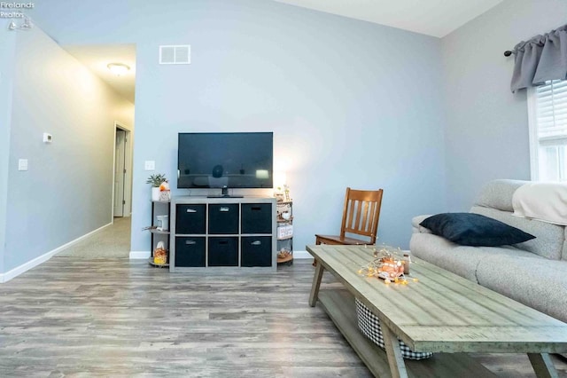 living room featuring visible vents, baseboards, and wood finished floors