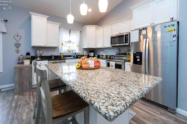 kitchen featuring vaulted ceiling, appliances with stainless steel finishes, a sink, and white cabinets