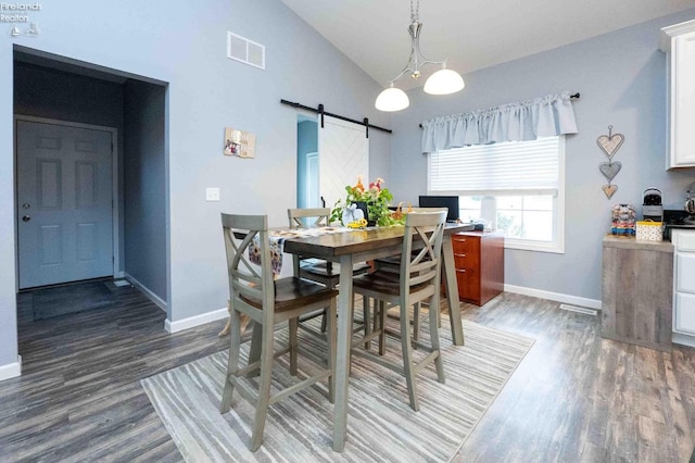 dining room featuring a barn door, baseboards, visible vents, wood finished floors, and high vaulted ceiling