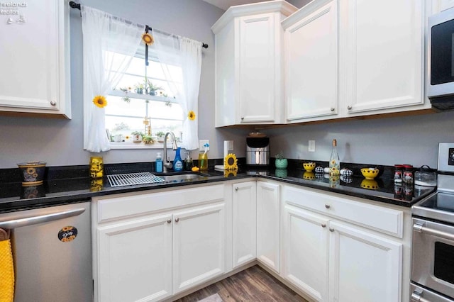 kitchen with white cabinetry, stainless steel appliances, a sink, and wood finished floors