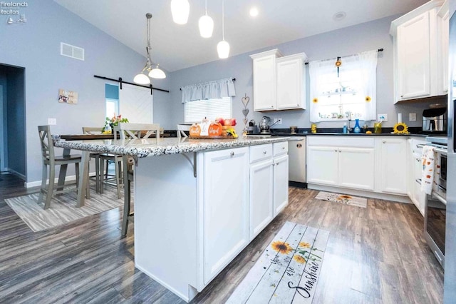 kitchen featuring white cabinets, dark wood finished floors, a breakfast bar area, and a barn door