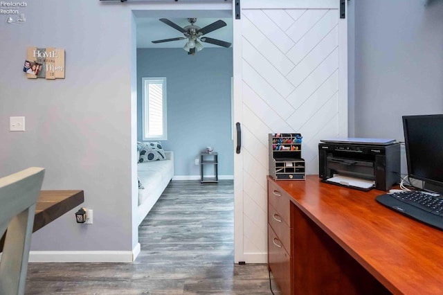 home office featuring dark wood-style floors, a barn door, baseboards, and a ceiling fan