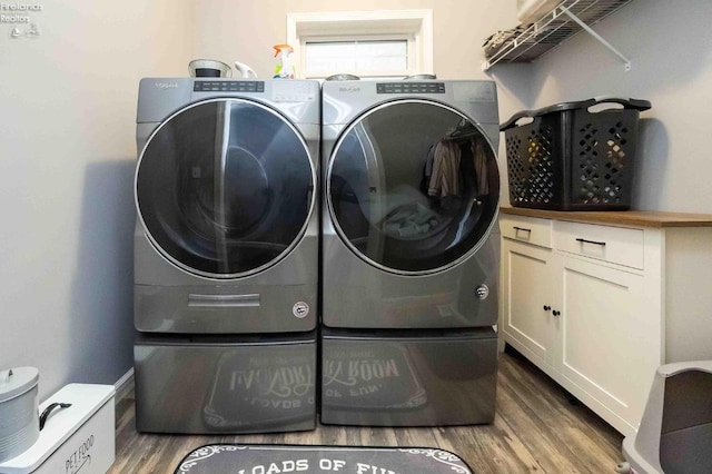 clothes washing area featuring laundry area, washing machine and dryer, and wood finished floors