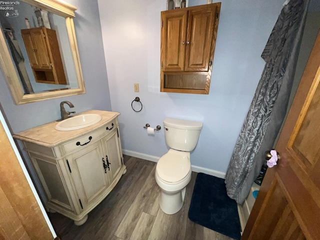 full bathroom with toilet, vanity, wood finished floors, a shower with curtain, and baseboards