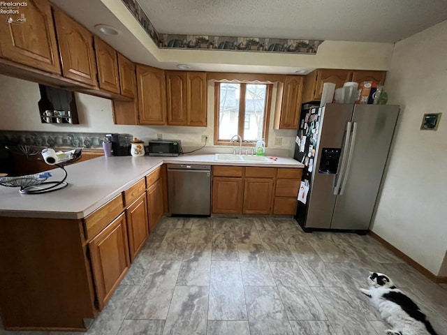 kitchen featuring light countertops, appliances with stainless steel finishes, brown cabinetry, and a sink