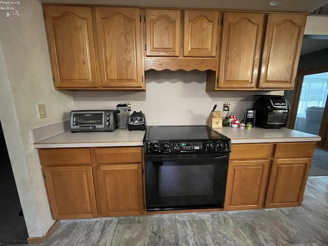 kitchen with light countertops, a toaster, and black electric range oven