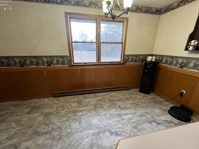 unfurnished dining area with wainscoting, a notable chandelier, wood walls, and baseboard heating