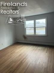 bonus room featuring a baseboard heating unit and wood finished floors