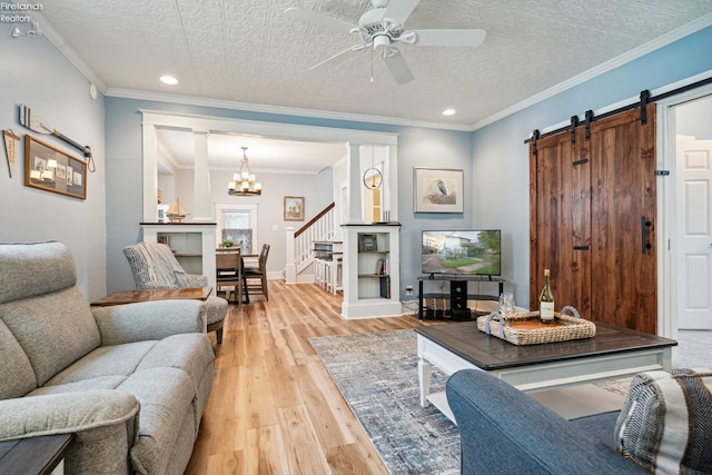 living area featuring light wood-type flooring, crown molding, a textured ceiling, and a barn door