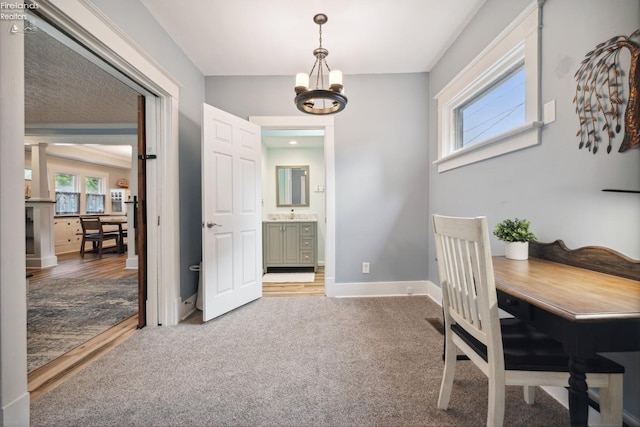 carpeted dining room featuring baseboards and an inviting chandelier