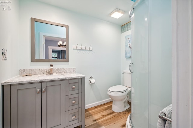 full bath featuring toilet, wood finished floors, vanity, baseboards, and a stall shower