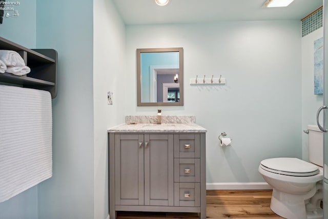 bathroom with vanity, wood finished floors, toilet, and baseboards