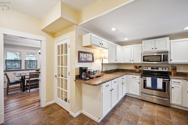 kitchen with stone finish flooring, appliances with stainless steel finishes, white cabinets, and recessed lighting