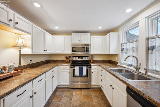 kitchen featuring dark countertops, recessed lighting, appliances with stainless steel finishes, white cabinetry, and a sink