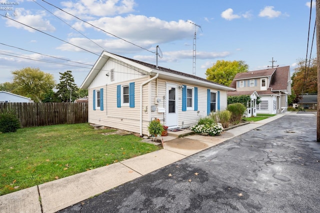 bungalow featuring a front lawn and fence