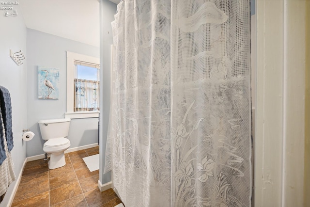 bathroom with curtained shower, baseboards, and toilet