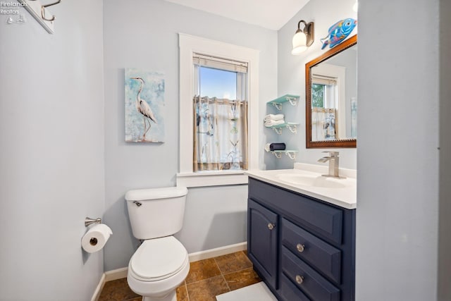 bathroom with baseboards, vanity, and toilet