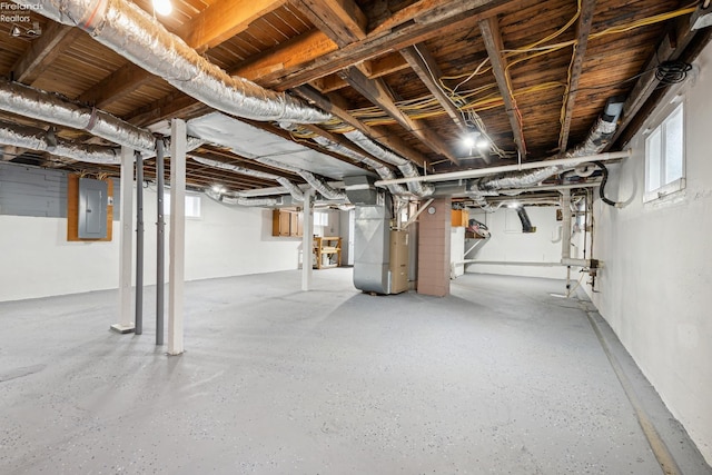 basement featuring heating unit, a healthy amount of sunlight, and electric panel