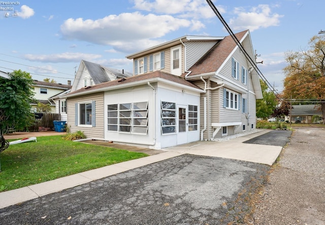 rear view of house featuring a shingled roof, a lawn, and fence