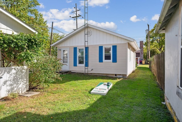 rear view of property featuring a yard and fence