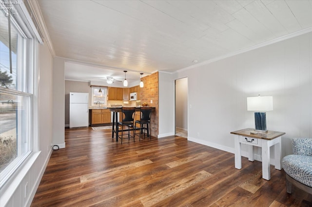 living room with baseboards, ornamental molding, and dark wood-style flooring