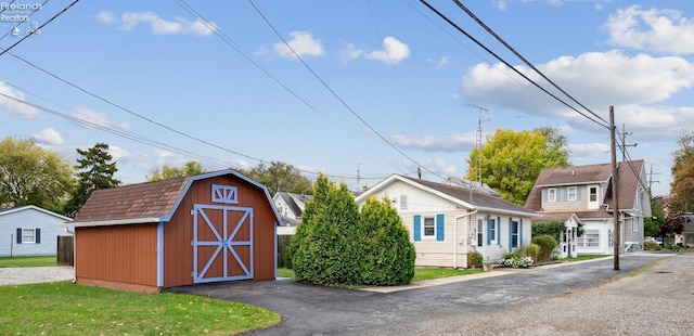 view of front of home with a front lawn, an outdoor structure, and a gambrel roof