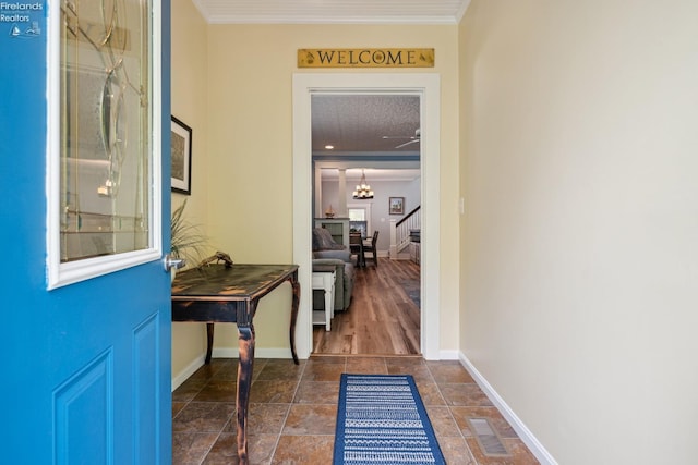 doorway to outside with crown molding, visible vents, baseboards, stairway, and an inviting chandelier