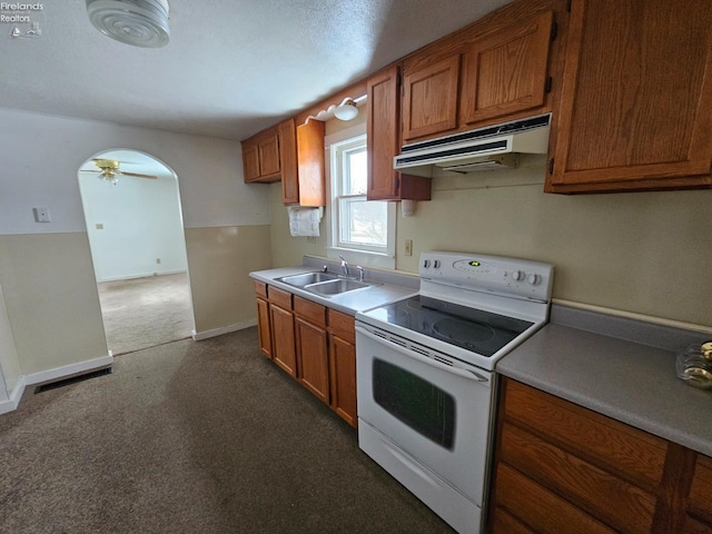 kitchen featuring arched walkways, range hood, electric range, brown cabinetry, and a sink