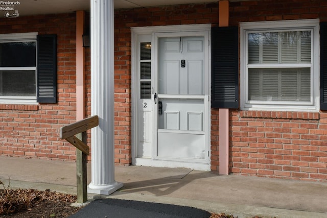 entrance to property featuring covered porch and brick siding