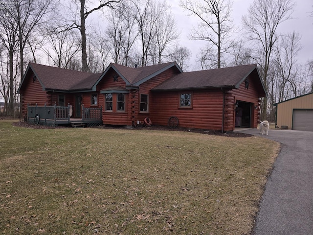 log home featuring log exterior, a shingled roof, a front yard, and a detached garage