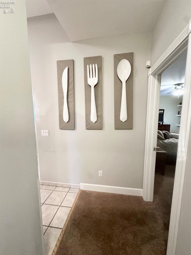 corridor featuring light carpet, light tile patterned floors, and baseboards