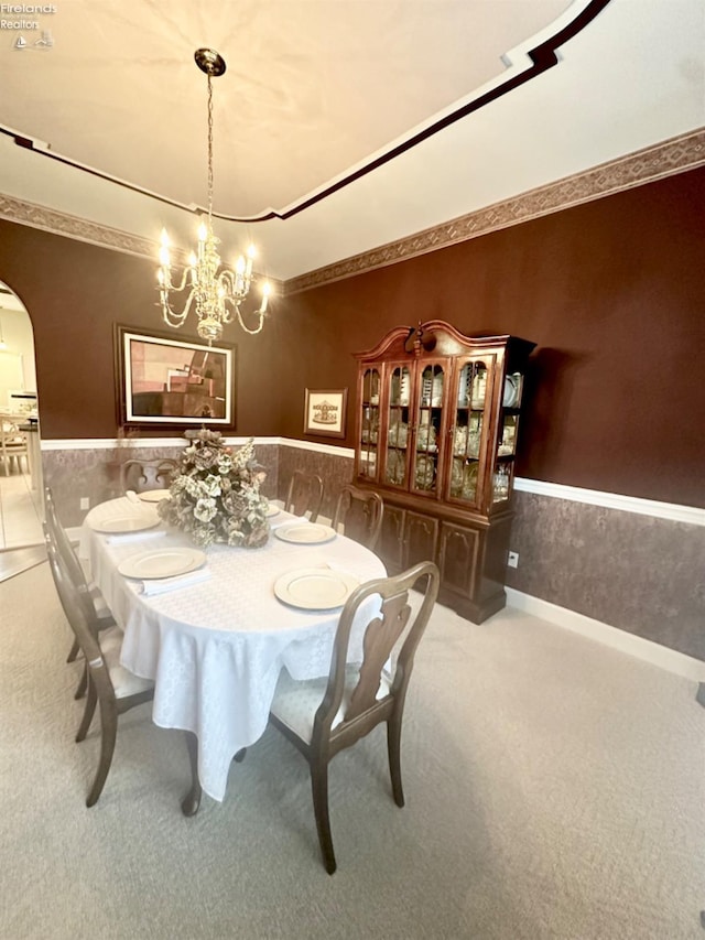 dining room featuring wallpapered walls, arched walkways, wainscoting, an inviting chandelier, and carpet