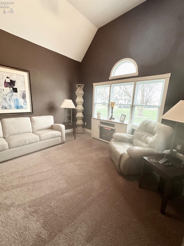 carpeted living area featuring baseboards and high vaulted ceiling