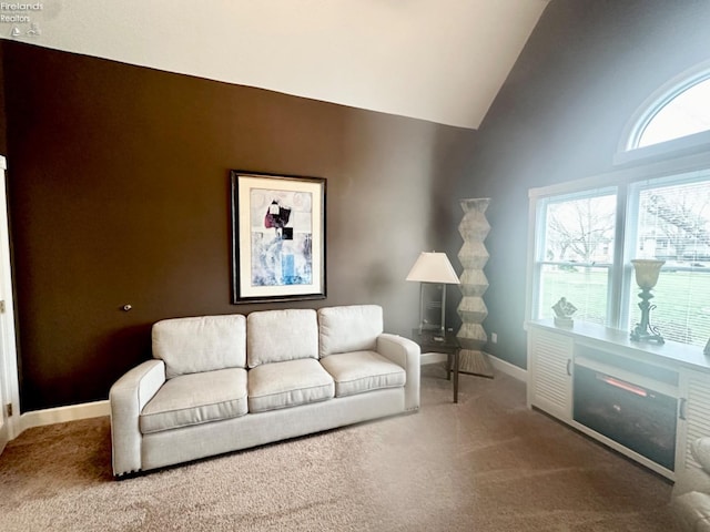 living area with carpet floors, high vaulted ceiling, and baseboards