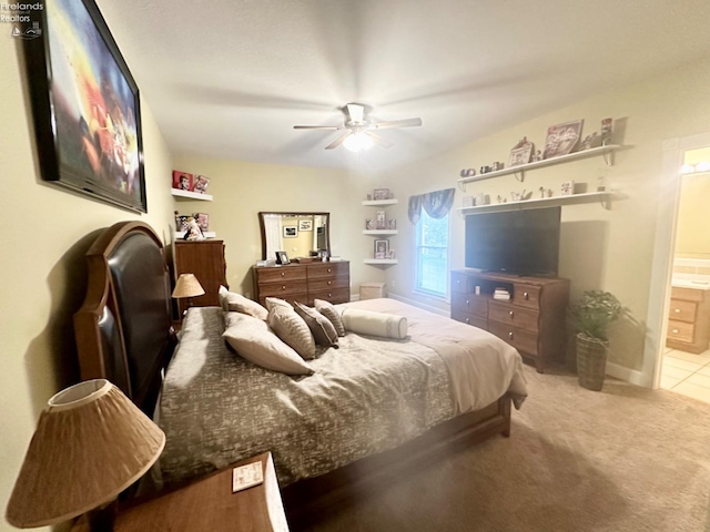 carpeted bedroom with a ceiling fan, tile patterned flooring, baseboards, and ensuite bathroom