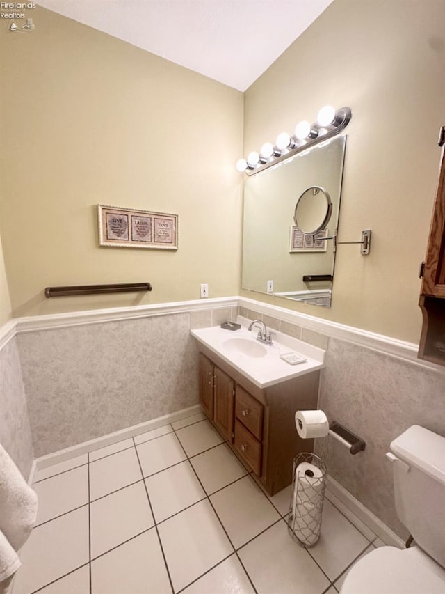 bathroom with toilet, tile walls, vanity, wainscoting, and tile patterned floors