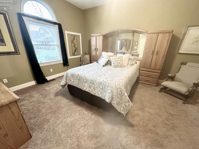 carpeted bedroom featuring multiple windows and baseboards