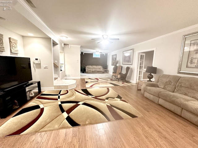 living room featuring crown molding, baseboards, ceiling fan, and wood finished floors