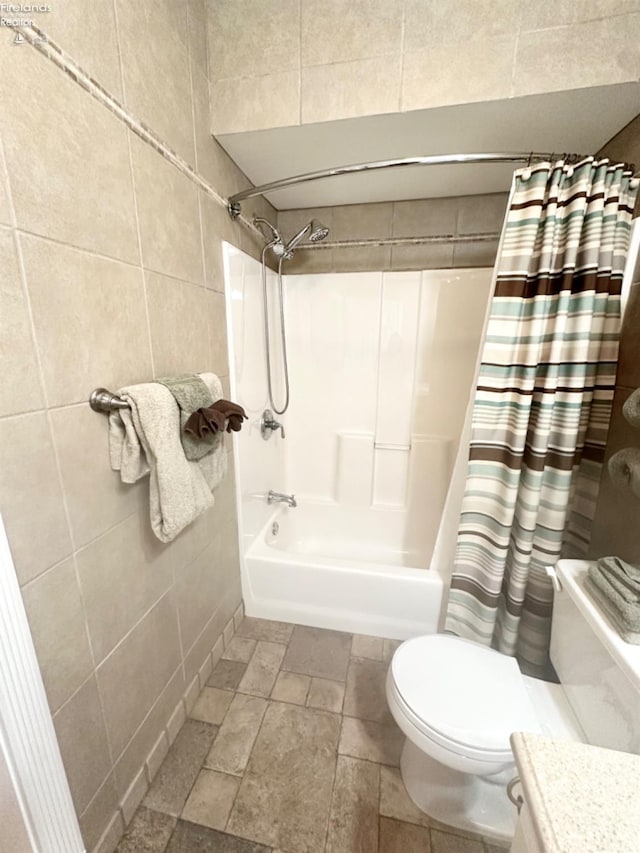 bathroom featuring toilet, shower / tub combo, stone finish flooring, and tile walls