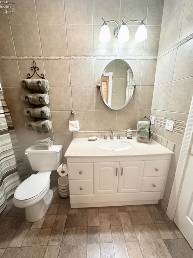 bathroom with toilet, vanity, and tile walls