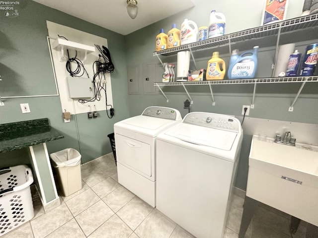 laundry room featuring light tile patterned floors, laundry area, separate washer and dryer, and a sink