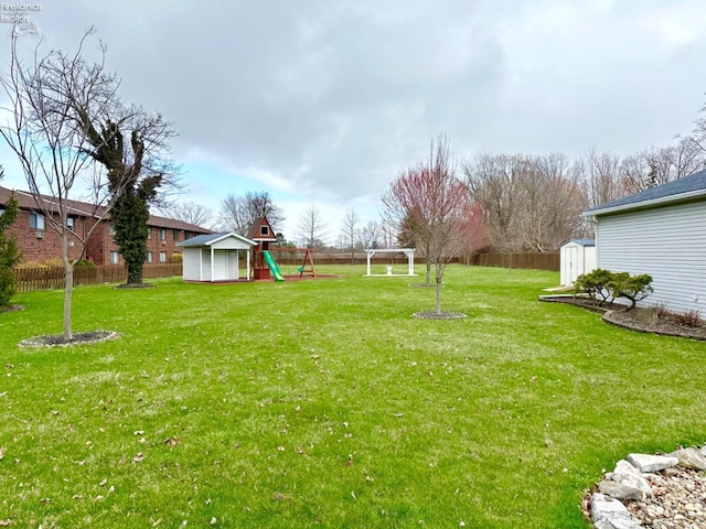 view of yard with a shed, a playground, a fenced backyard, and an outdoor structure