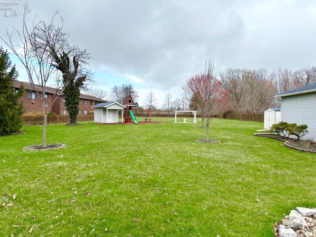 view of yard with a storage shed, a playground, a fenced backyard, and an outdoor structure