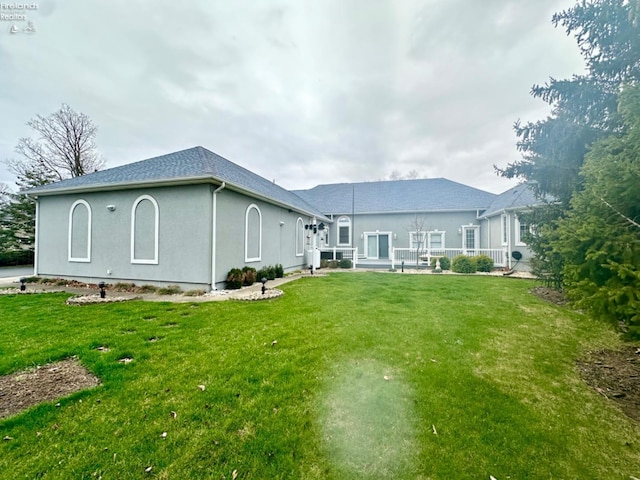 rear view of house with a lawn and stucco siding