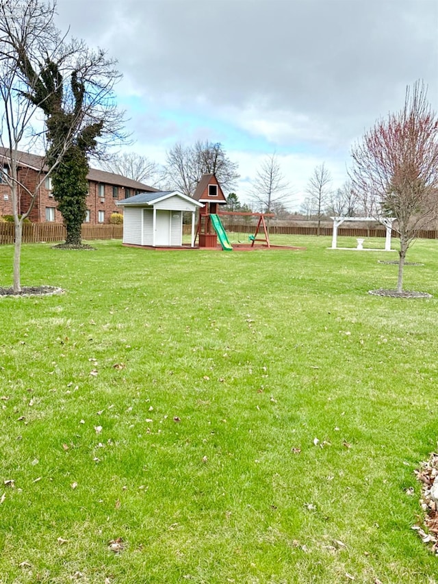 view of yard featuring a fenced backyard, a storage unit, a playground, and an outdoor structure