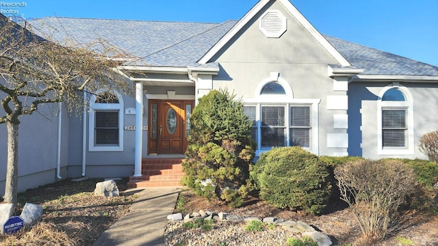 view of front of property with roof with shingles and stucco siding