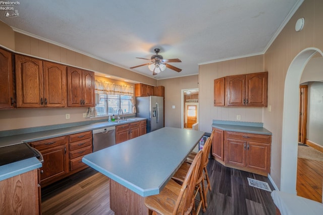 kitchen with a sink, dark wood-style floors, brown cabinets, and stainless steel appliances