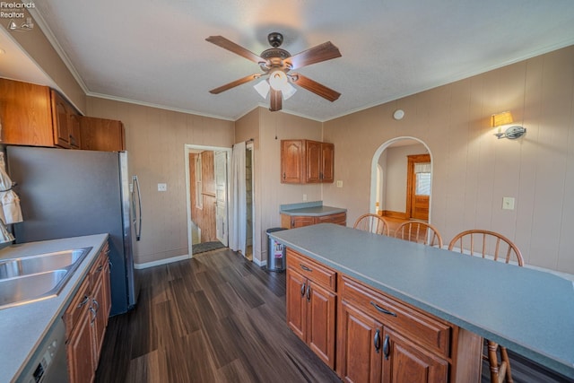 kitchen with dark wood-style floors, brown cabinetry, arched walkways, a sink, and dishwasher