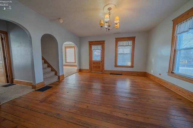 foyer entrance with hardwood / wood-style flooring, baseboards, visible vents, and a textured ceiling