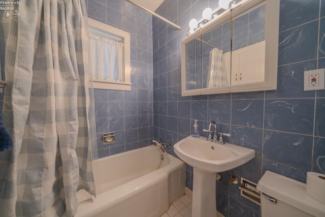 bathroom featuring tile patterned floors, shower / bathtub combination with curtain, toilet, a sink, and tile walls